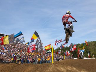 Karlis Reisulis im Sprung vor den Fahnen der Nationen beim Motocross of Nations 2026 in Ernée