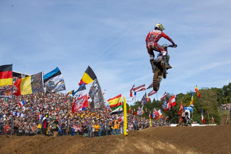 Karlis Reisulis im Sprung vor den Fahnen der Nationen beim Motocross of Nations 2026 in Ernée