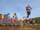 Karlis Reisulis im Sprung vor den Fahnen der Nationen beim Motocross of Nations 2026 in Ernée