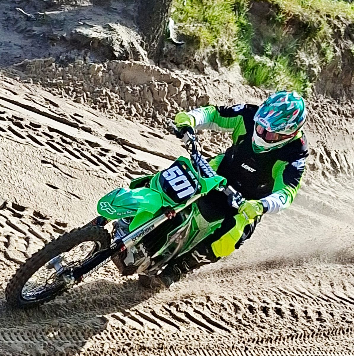 Dirk Pohl mit der Startnummer 501 auf seiner grünen Kawasaki KX450 in einer Sandkurve