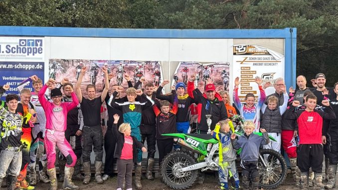 Lehrgangsteilnehmer jubeln mit erhobenen Armen hinter Dirk Pohls grüner Kawasaki mit der Startnummer 501 und einem Pokal