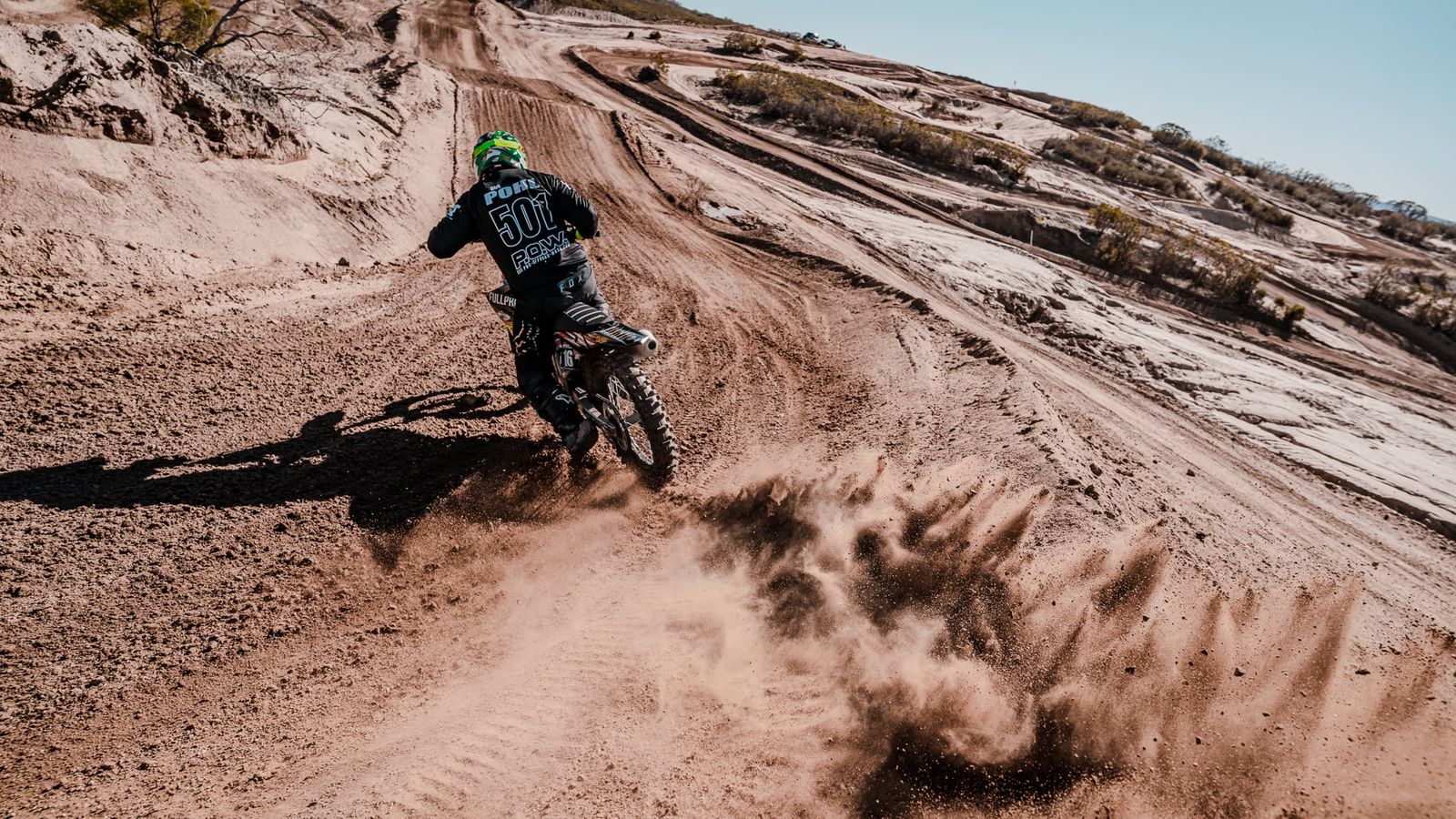 Motocross-Fahrer in einer sandigen Kurve auf einer Strecke in Kalifornien