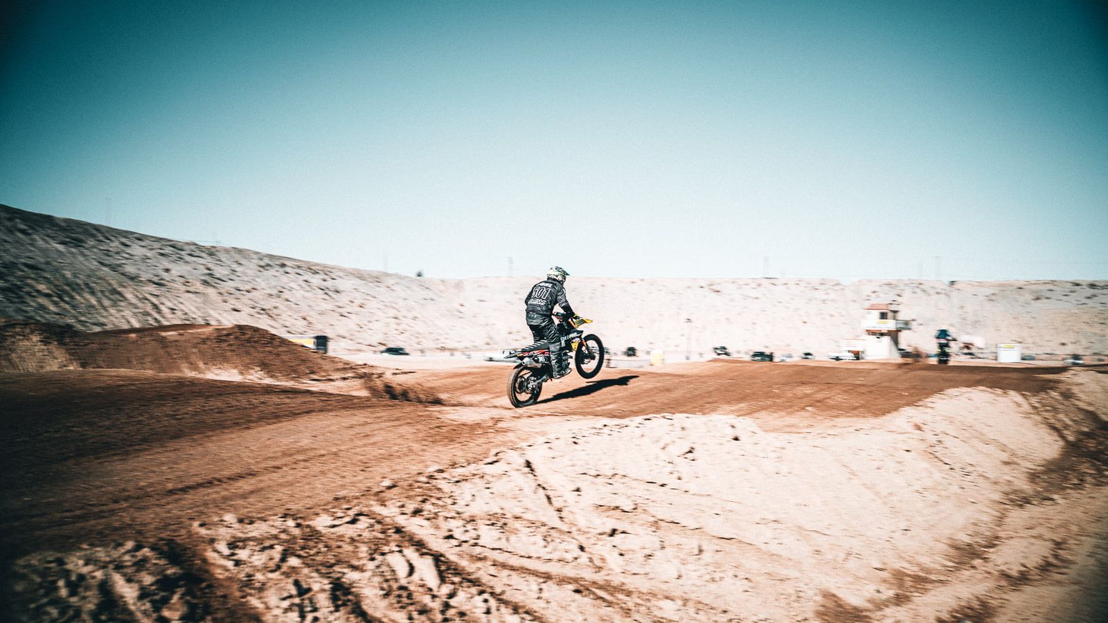 Motocross-Fahrer auf einer Sandstrecke vor hohen Dünen in Kalifornien