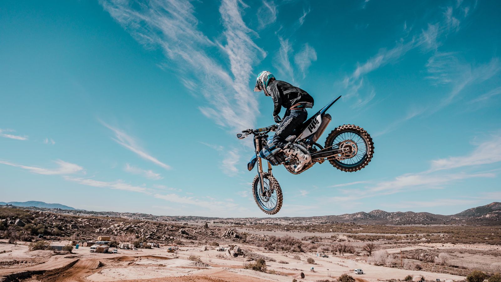 Motocross-Fahrer mit Whip hoch über der Wüstenlandschaft Südkaliforniens
