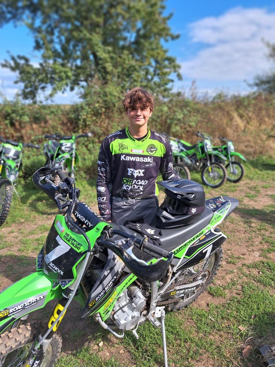 Junger Fahrer im Outfit der OFF-ROAD SCHOOL Germany neben einer Kawasaki KLX