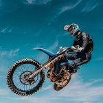 Motocross-Fahrer im Sprung vor blauem Himmel bei der Motocross-Reise von Kiedrowski Motorsports nach Kalifornien