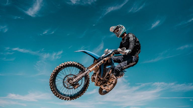 Motocross-Fahrer im Sprung vor blauem Himmel bei der Motocross-Reise von Kiedrowski Motorsports nach Kalifornien