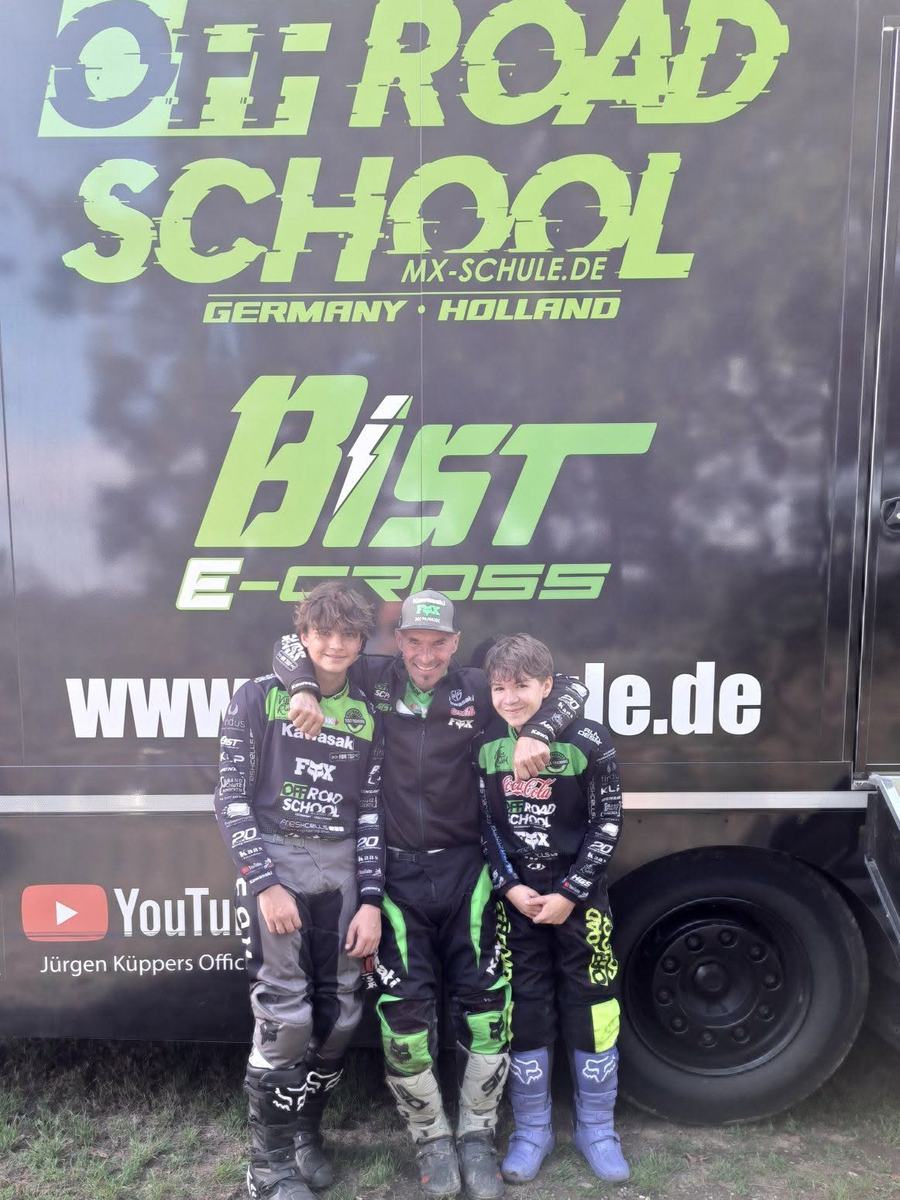 Trainer der OFF-ROAD SCHOOL Germany mit zwei Kindern vor dem Truck der Motocross-Schule